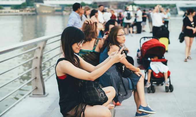 A woman takes a picture in Singapore. Photo by Unsplash/Annie Spratt