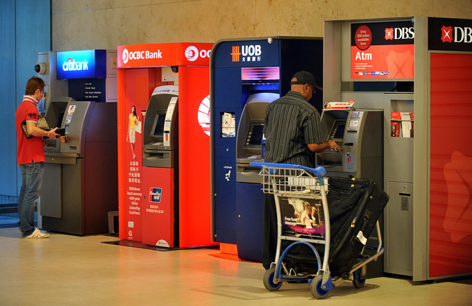 Automated Teller Machines (ATMs) from Citibank, OCBC, UOB and DBS line the wall in Changi Airport Terminal 2, Nov. 28, 2011. Photo by SPH Media via AFP