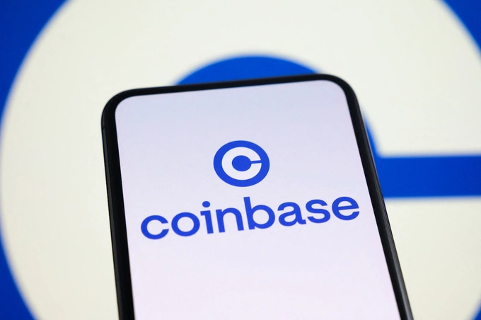 The logo of Coinbase is displayed on a smartphone screen with the company logo in the background, in Créteil, France, on June 30, 2026. Photo by NurPhoto via AFP