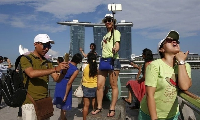 Tourists pose for photos with the Marina Bay Sands at a popular tourist spot along Marina Bay in Singapore, July 24, 2015. Photo by Reuters