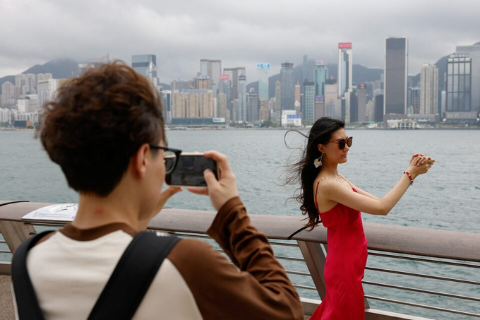 Tourists poses for photos in front of Victoria Harbor in Hong Kong, April 30, 2024. Photo by Reuters