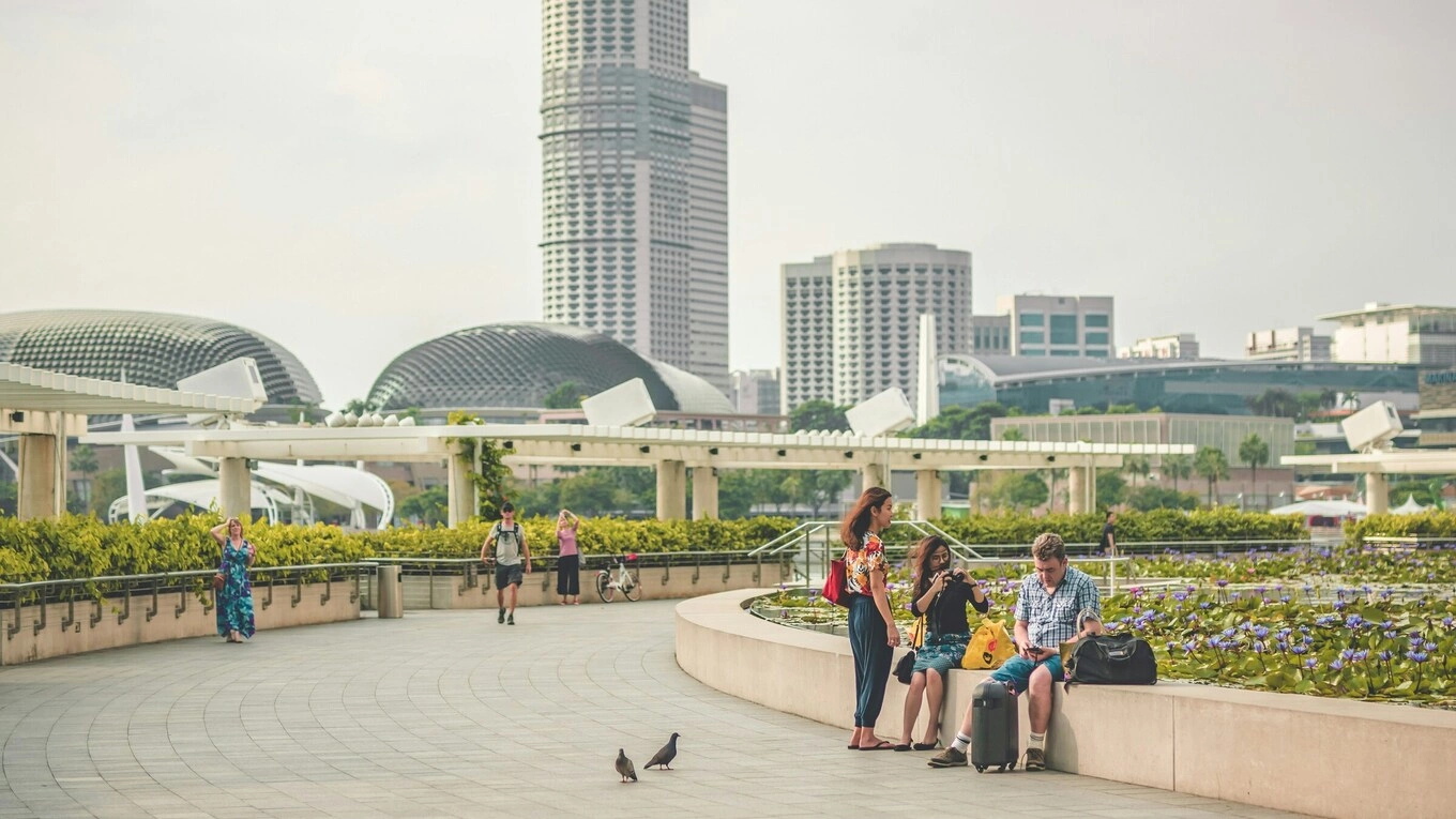 Tourists relax at Marina Bay in Singapore, with the Esplanade and city skyline in the background. Photo by Jeremy Julian/Unsplash