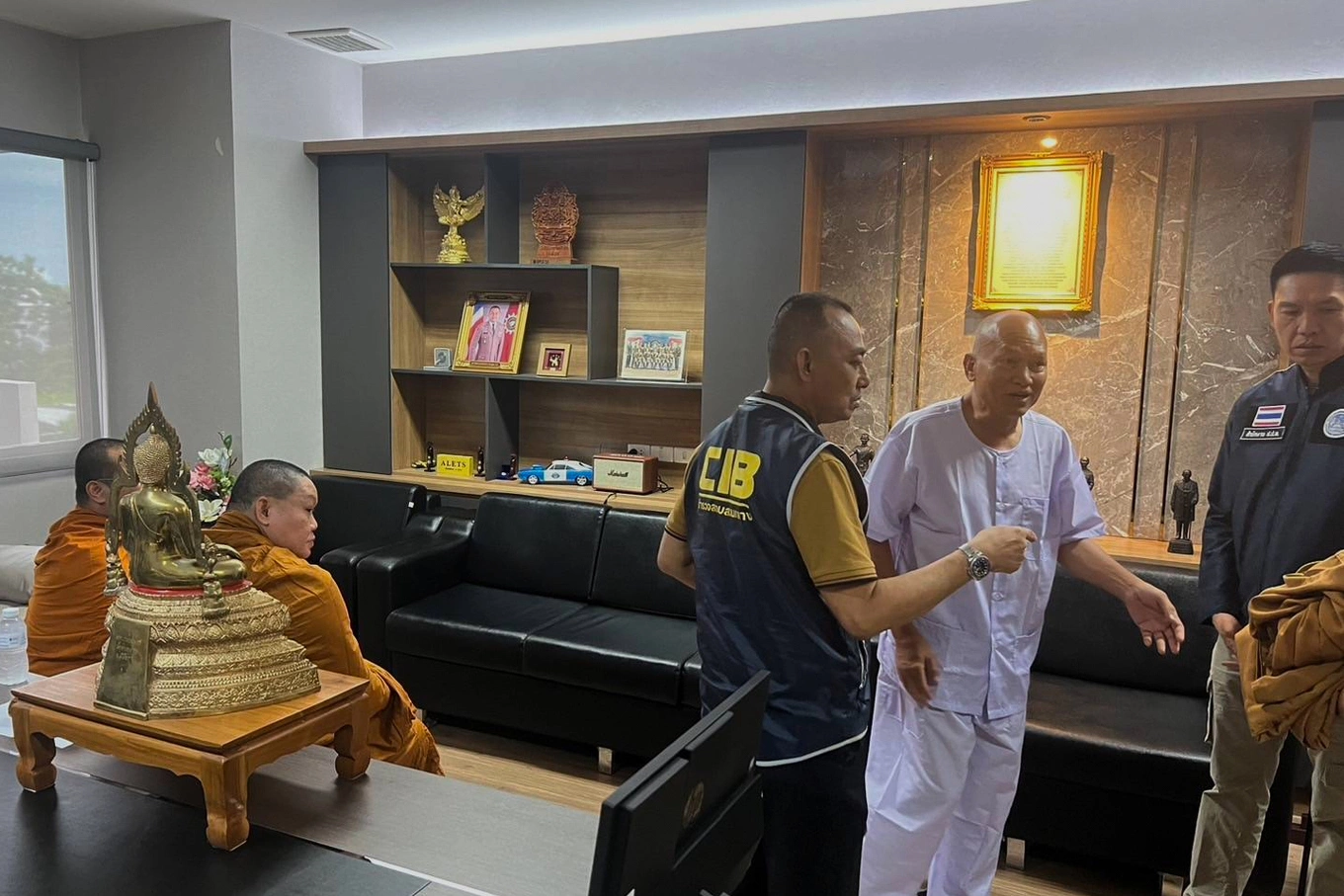 In this photo released by the Central Investigation Bureau, Alongkot Poonmook, formerly known as Phra Ratcha Wisutthiprachanat, second right in white, talks to police personnel at the Central Investigation Bureau in Bangkok, Thailand, Aug. 26, 2025. Photo by AP