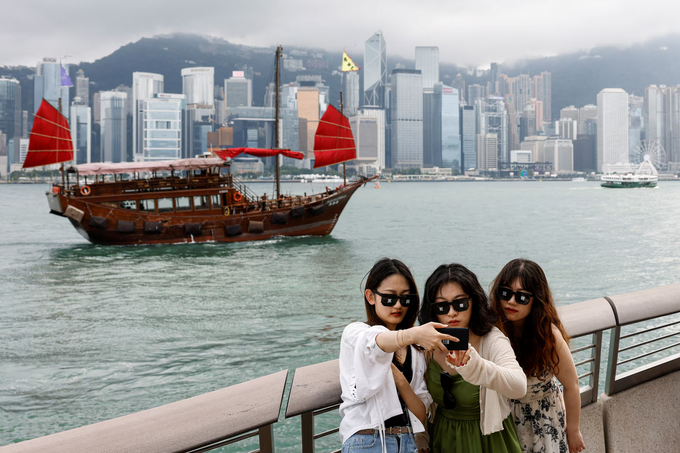 Tourists take photos in front of Victoria Harbour, in Tsim Sha Tsui, in Hong Kong, April 29, 2024. Photo by Reuters