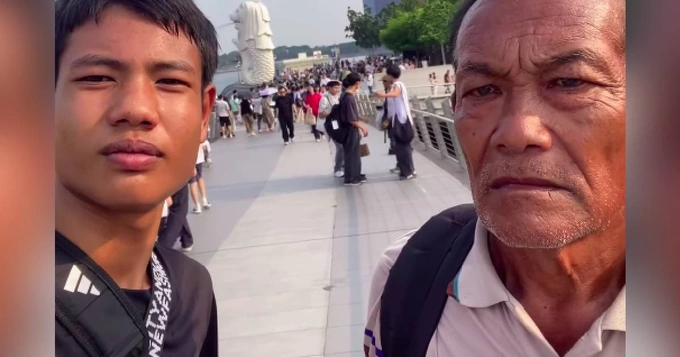 A photo shared on social media shows Queue and his grandfather posing for photos near the iconic Merlion statue in Singapore.