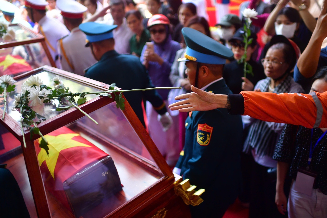 Residents place white chrysanthemums to pay their respects as the remains of fallen soldiers are taken to the city cemetery for reburial on Oct. 14, 2026.