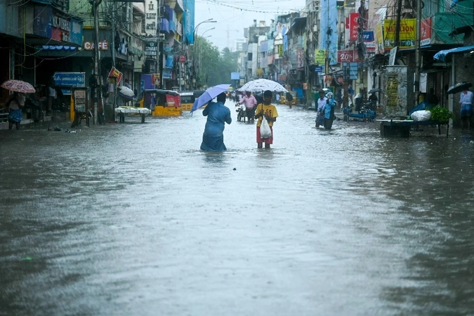 People wade through a flooded street as it rains ahead of a cyclonic storm in Chennai. Photo by AFP