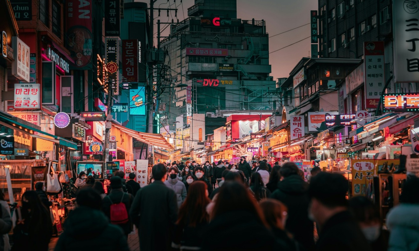 People walk along a busy shopping street in South Korea. Photo by zero take/Unsplash